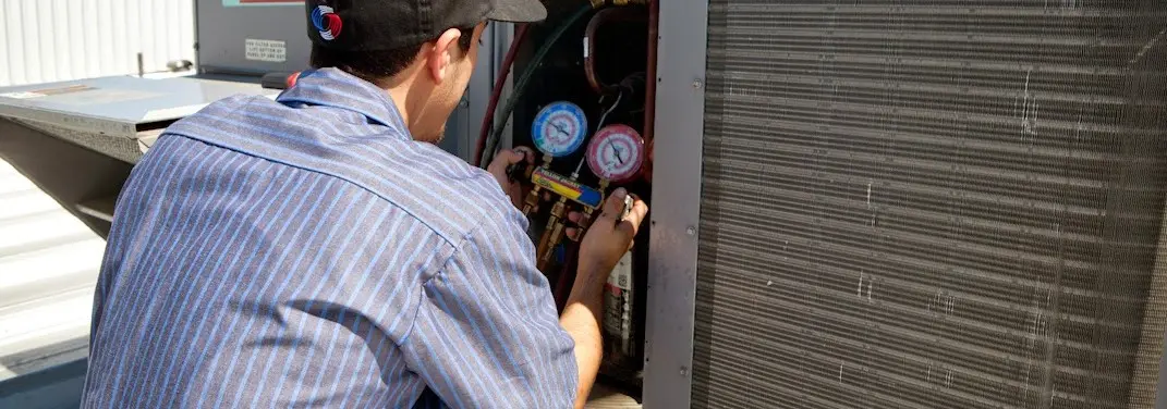 HVAC technician servicing a condenser unit in Auburn