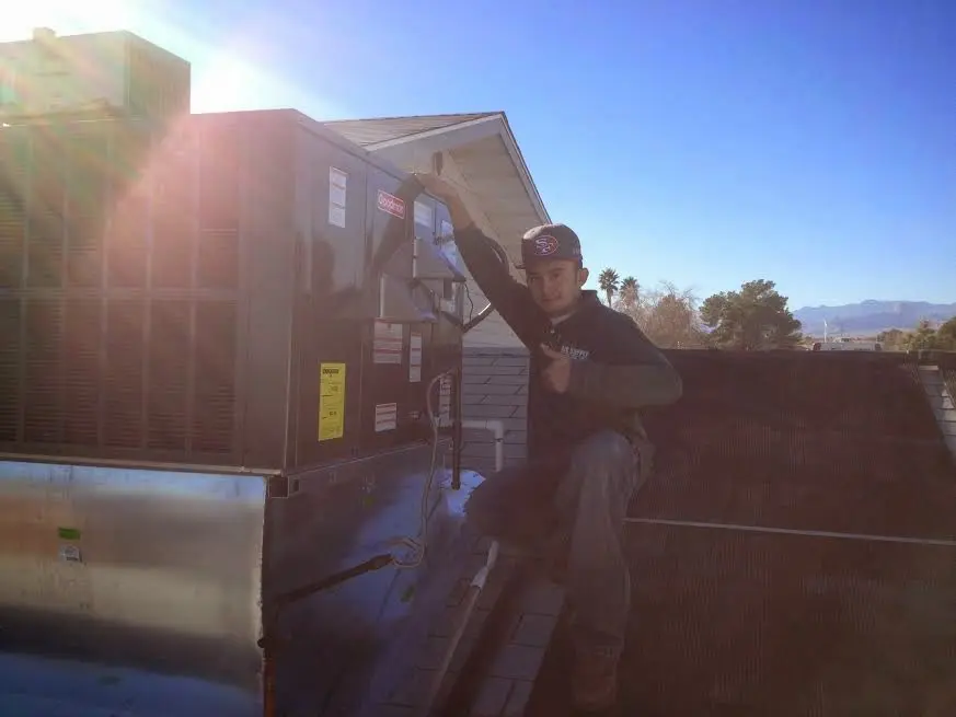 HVAC technician performing AC Tune-Up on a rooftop unit in Auburn